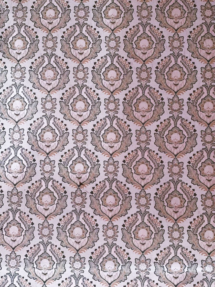 Close-up of a mauve and gray damask wallpaper showing its repeating ornamental motif